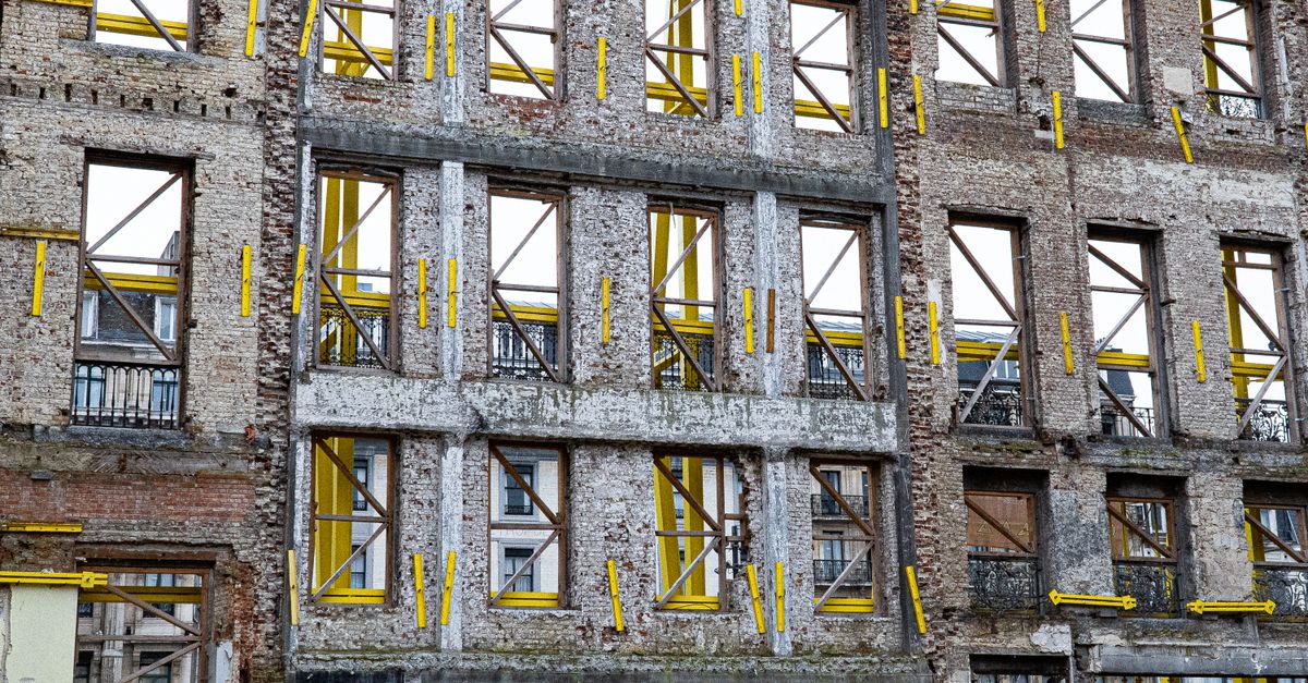 A historic building facade under renovation in urban Brussels with yellow supports.